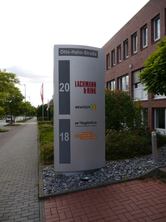 Im Eingangsbereich des Gebäudes in der Otto-Hahn-Straße 20 repräsentiert ein großes Schild die im Gebäude befindenden Bereiche